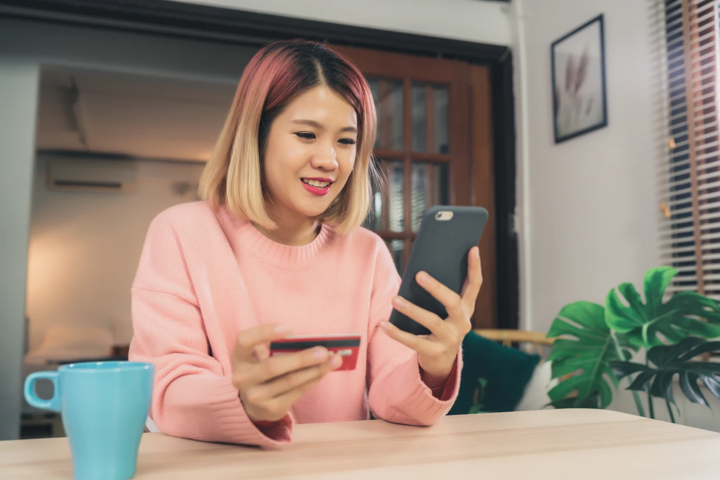 Customer using a smartphone while holding a payment card at home