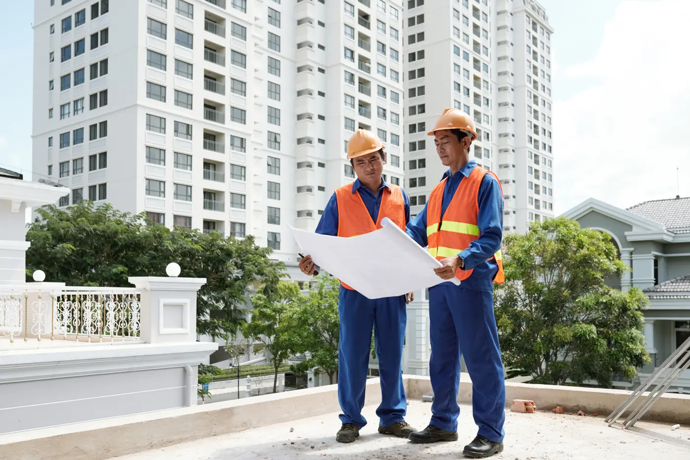 Two engineers checking construction drawings outside a residential development