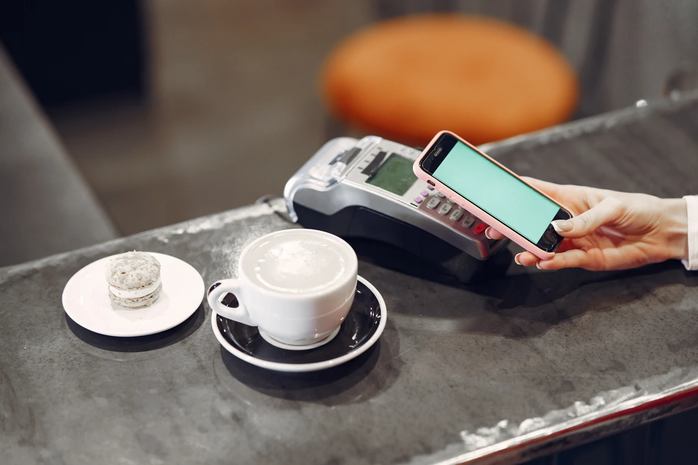 Customer using a smartphone for contactless payment at a cafe