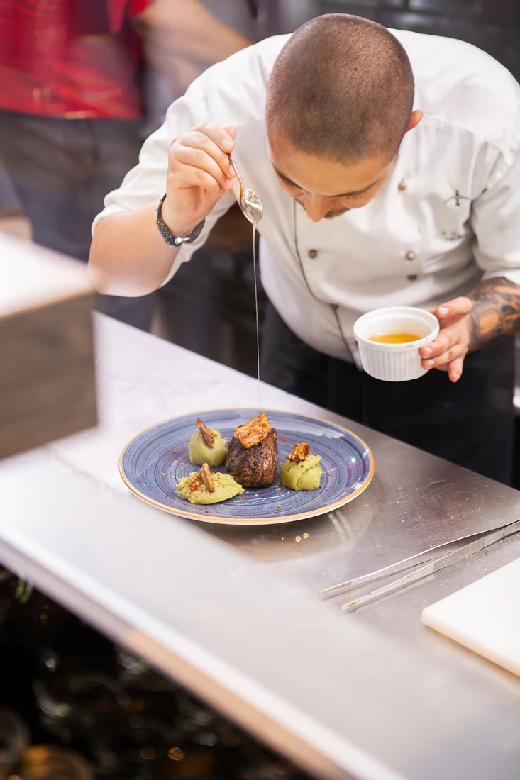 Chef carefully finishing a plated restaurant dish